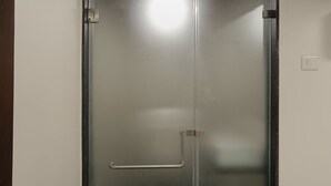 A closed door with a handle and a latch, a light switch on the wall, and a small window at the bottom. - AR Residency (Mumbai)