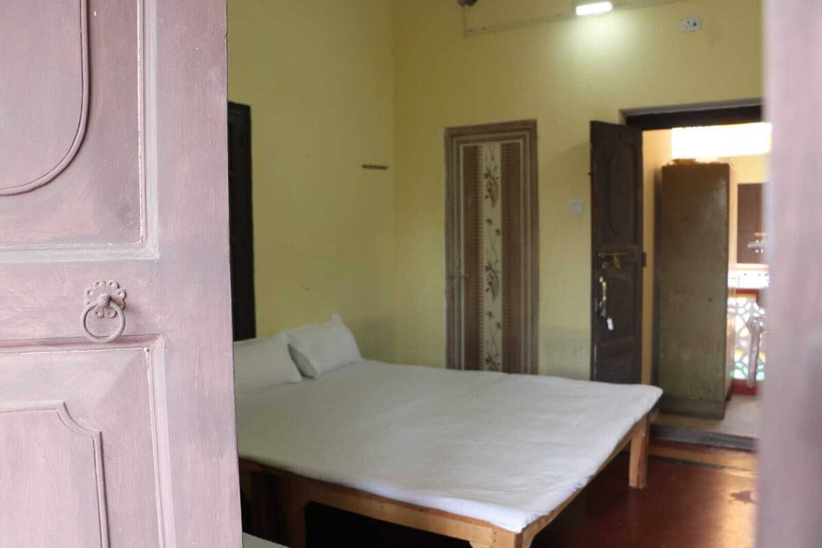 A room with a bed, a door, and a view of another room.