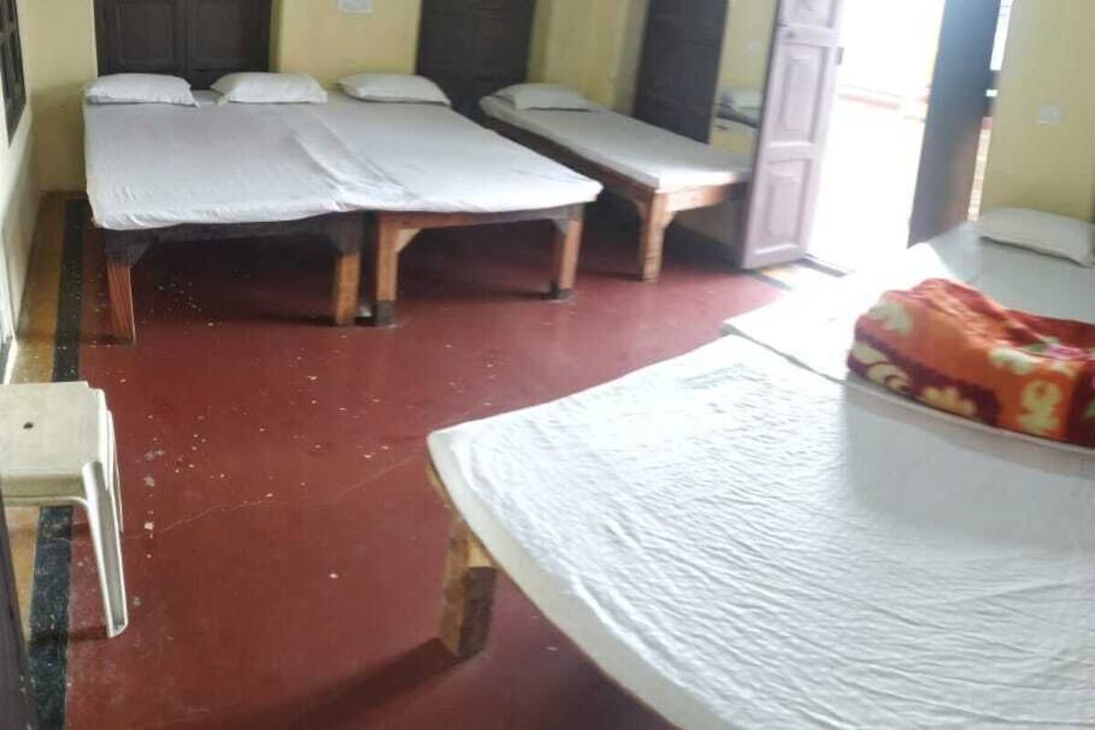 A room with two beds, a bench, and a small table.