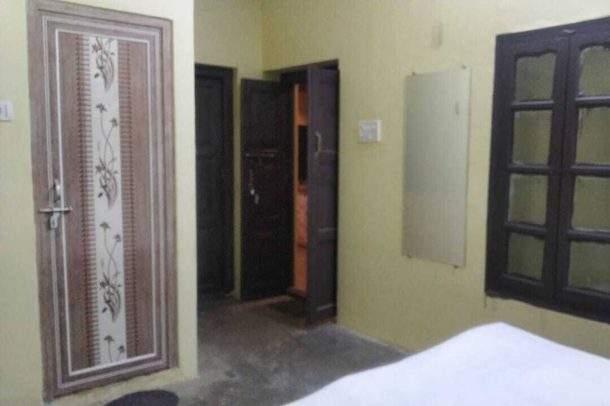A room with a bed, a door with a decorative panel, and a window with a frosted glass panel.