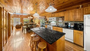 A wooden cabin interior with a kitchen, dining area, and a cozy living space. - Smoky Mountain Getaway: Leave the World Behind (Pigeon Forge)