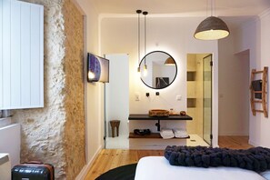 A modern bedroom with a large bed, a round mirror, a wooden shelf with toiletries, and a wooden floor. - Sonel Investe Anjos Boutique Apartments (Lisbon)