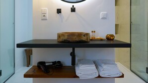 A bathroom with a wooden vanity, a round mirror, and a towel rack.