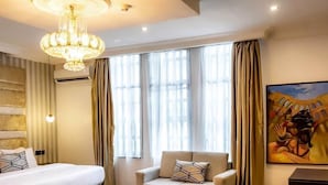 Een hotelkamer met een bed, een bank, een kleine tafel en een schilderij aan de muur.