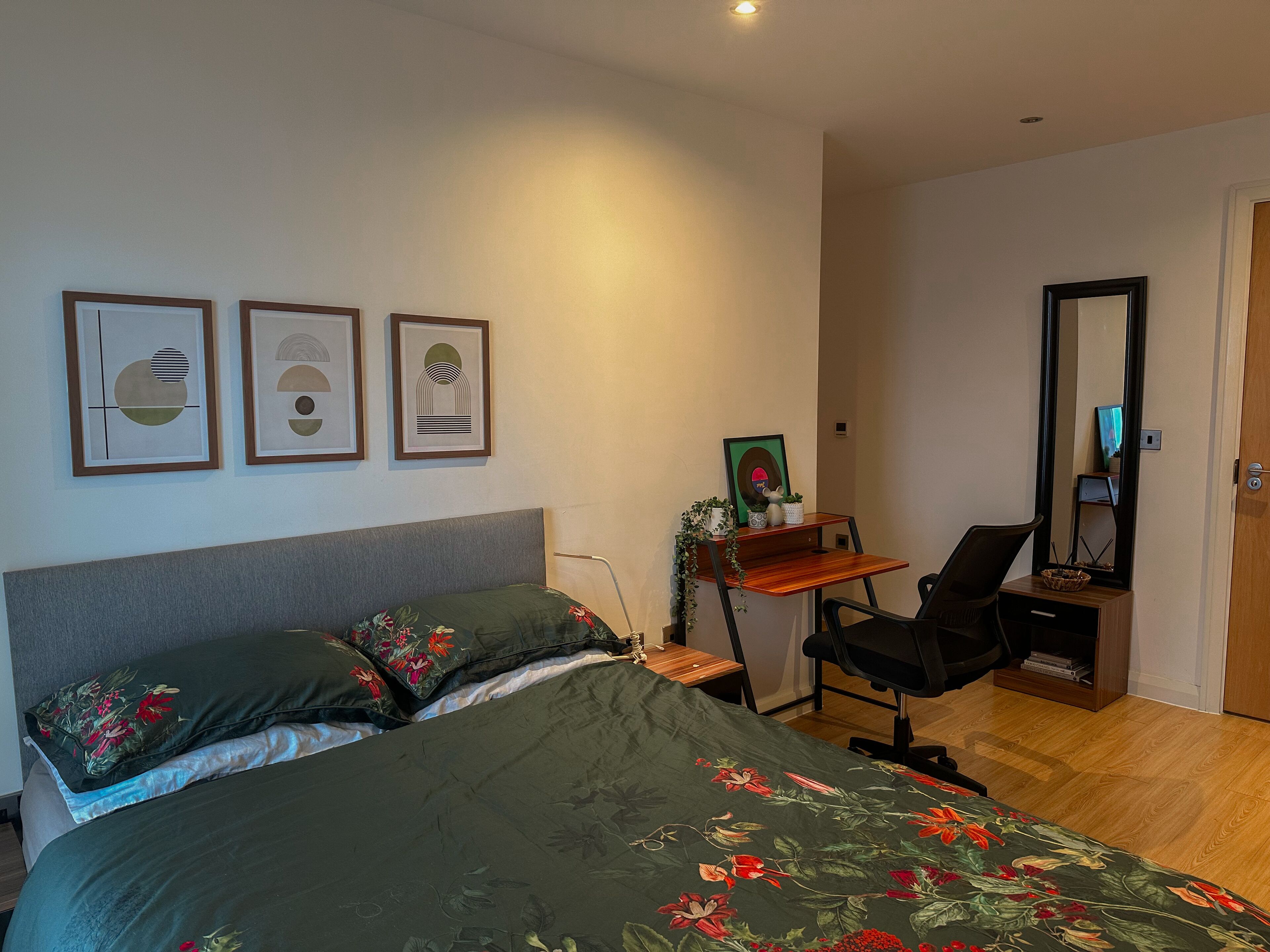 Un dormitorio con cama, escritorio, silla y espejo.