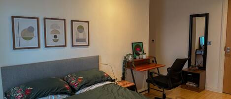 Un dormitorio con cama, escritorio, silla y espejo.