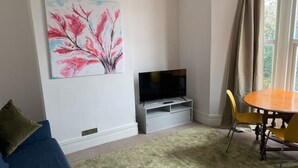 A living room with a TV, a painting, a dining table with chairs, and a sofa. - Central 2 bed flat. Free parking (Off-street) (Bristol)