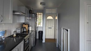 A narrow kitchen with stainless steel appliances, a black countertop, and a white door leading to another room. - Seaview/downs National Park & Free Parking (Brighton)
