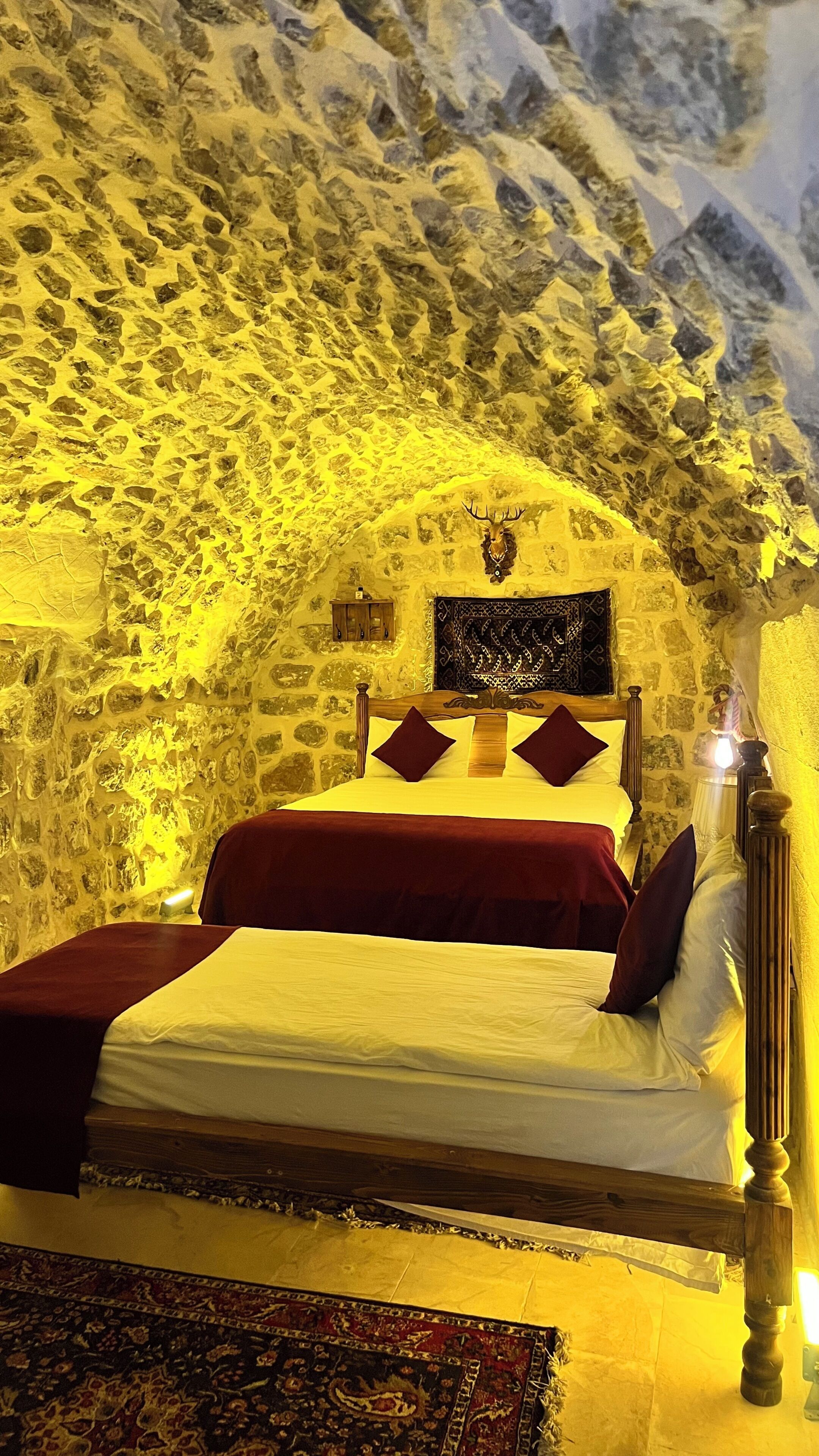 A bed in a room with a stone wall and a wooden headboard.
