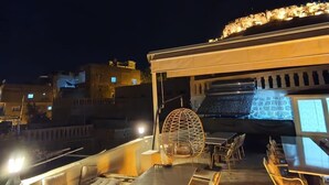 Un área de comedor al aire libre con una pared de piedra, una silla colgante y una mesa con sillas.