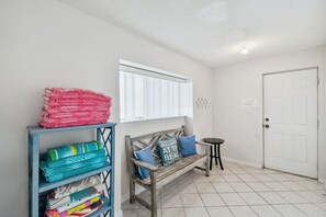 A room with a bench, a small table, and a shelf with folded blankets. - Dolphin View Oceanfront Home with Rooftop Deck (Ponte Vedra Beach)