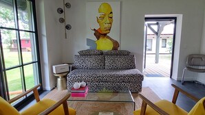 A modern living room with a sofa, two yellow chairs, a coffee table, and a painting on the wall.