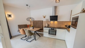 A modern kitchen with a dining area, featuring a wooden table, chairs, and a pendant light. - 068 Whkb 7 in St Georgen am Kreischberg (Sankt Georgen am Kreischberg)