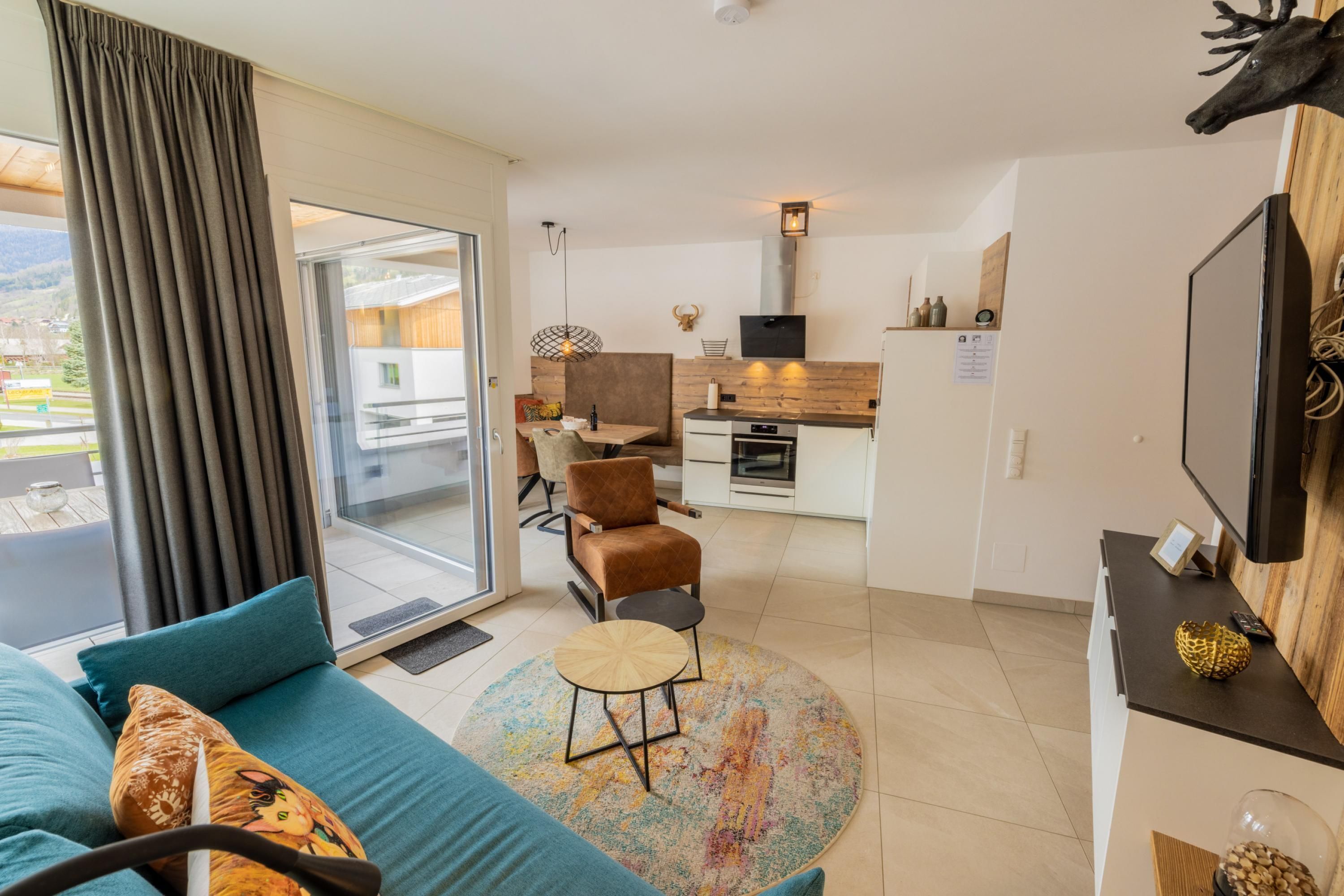 Een moderne woonkamer met een bank, een salontafel en uitzicht door een glazen deur op een buitenruimte.