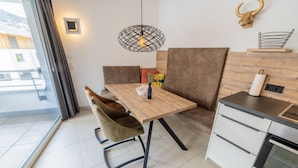 A modern kitchen with a wooden table, two chairs, a hanging light fixture, and a kitchen counter with a built-in oven. - 068 Whkb 7 in St Georgen am Kreischberg (Sankt Georgen am Kreischberg)