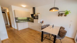 Una cucina moderna con mobili bianchi, forno integrato e zona pranzo con tavolo e sedie.