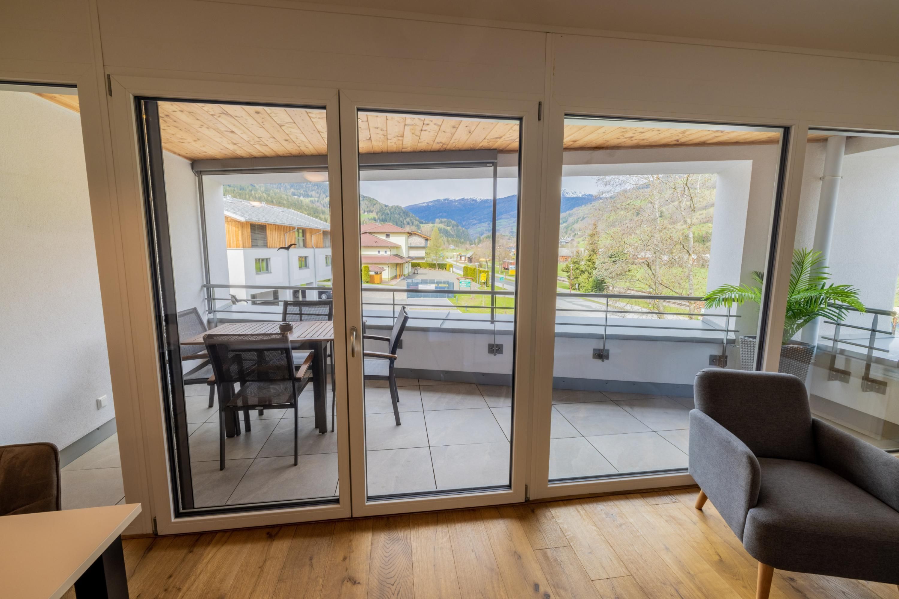 Een modern interieur met een schuifglazen deur naar een balkon met een eettafel en stoelen.