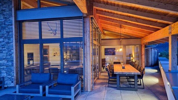 An outdoor seating area with a wooden table and chairs, stone walls, and a view of the interior. - 070 Phkb9 in St Georgen am Kreischberg (Sankt Georgen am Kreischberg)