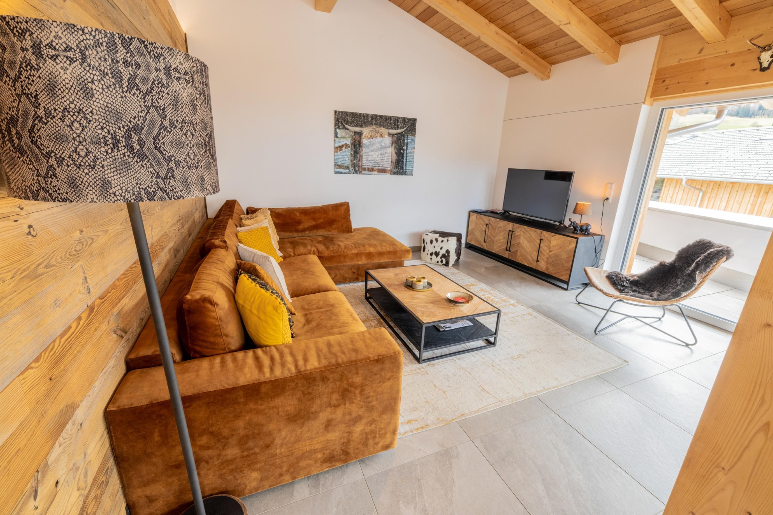 A modern living room with a brown sofa, a glass coffee table, a TV, and a wooden cabinet.