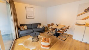 A modern living room with a sofa, coffee table, ottoman, and dining area with chairs and a table. - 064 Whkb 3 in St Georgen am Kreischberg (Sankt Georgen am Kreischberg)