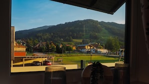 A view from a window overlooking a rural landscape with houses, a hotel, and a mountain in the background.