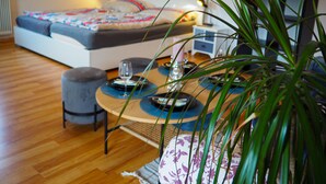 A modern bedroom with a bed, bedside table, and a small seating area with a table and chairs.