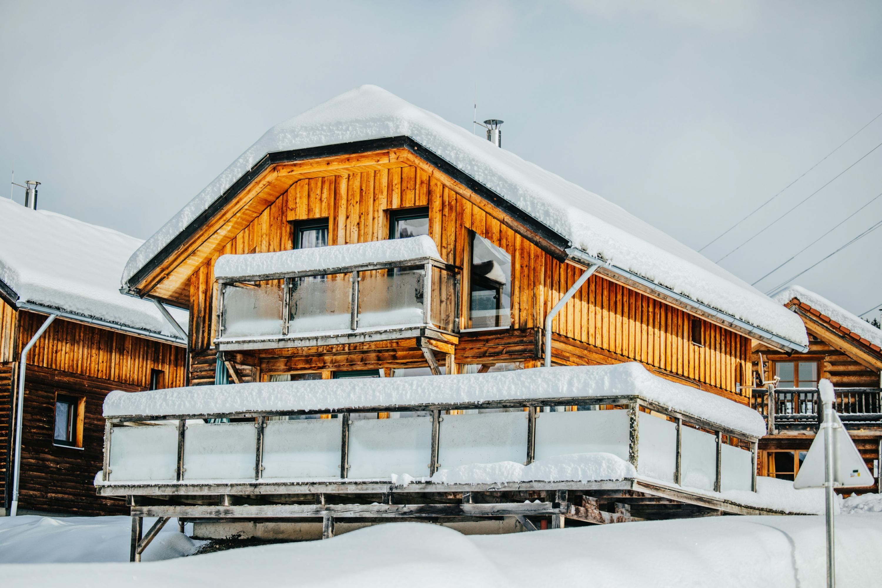 A wooden chalet with a balcony, surrounded by snow.