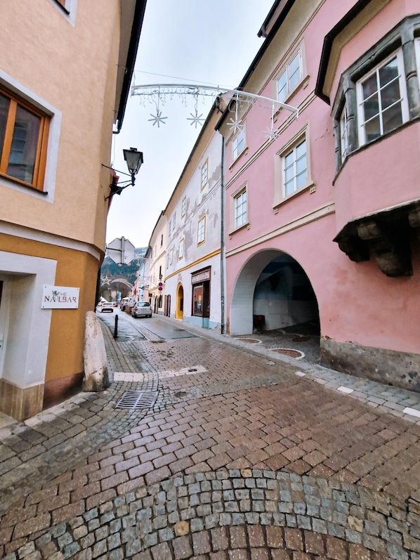 A cobblestone street with historic buildings, a sign for 'The Nalbar', and a pedestrian archway.