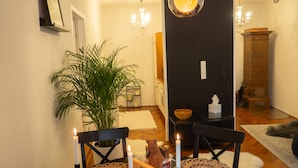 Een gezellige eethoek met een tafel gedekt voor twee personen, inclusief een kaarsdecoratie, een potplant en een houten doos.