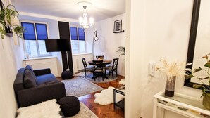 Een moderne woonkamer met een bank, een salontafel, en een eethoek met een tafel en stoelen.