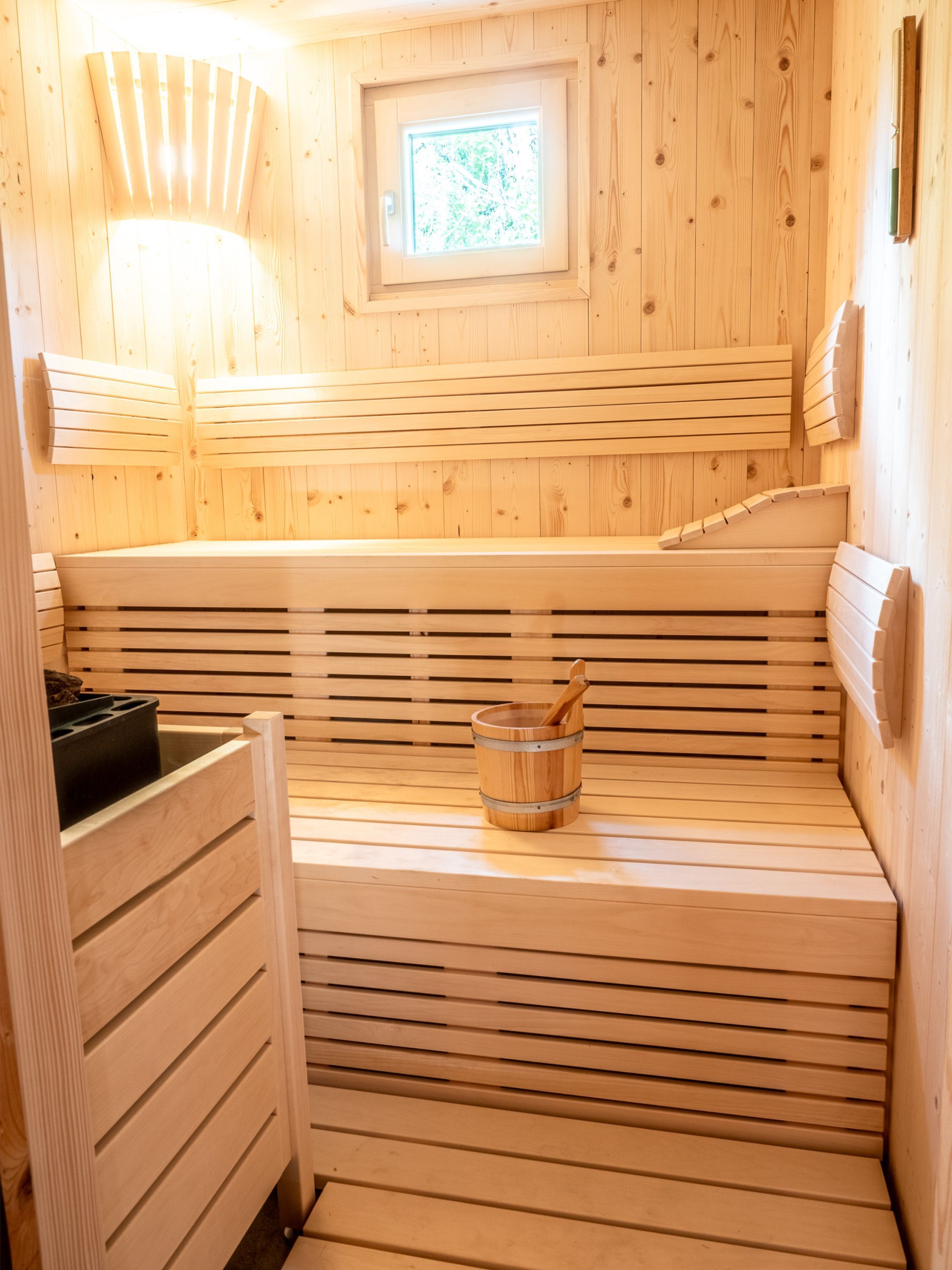 A wooden sauna with benches and a small window.