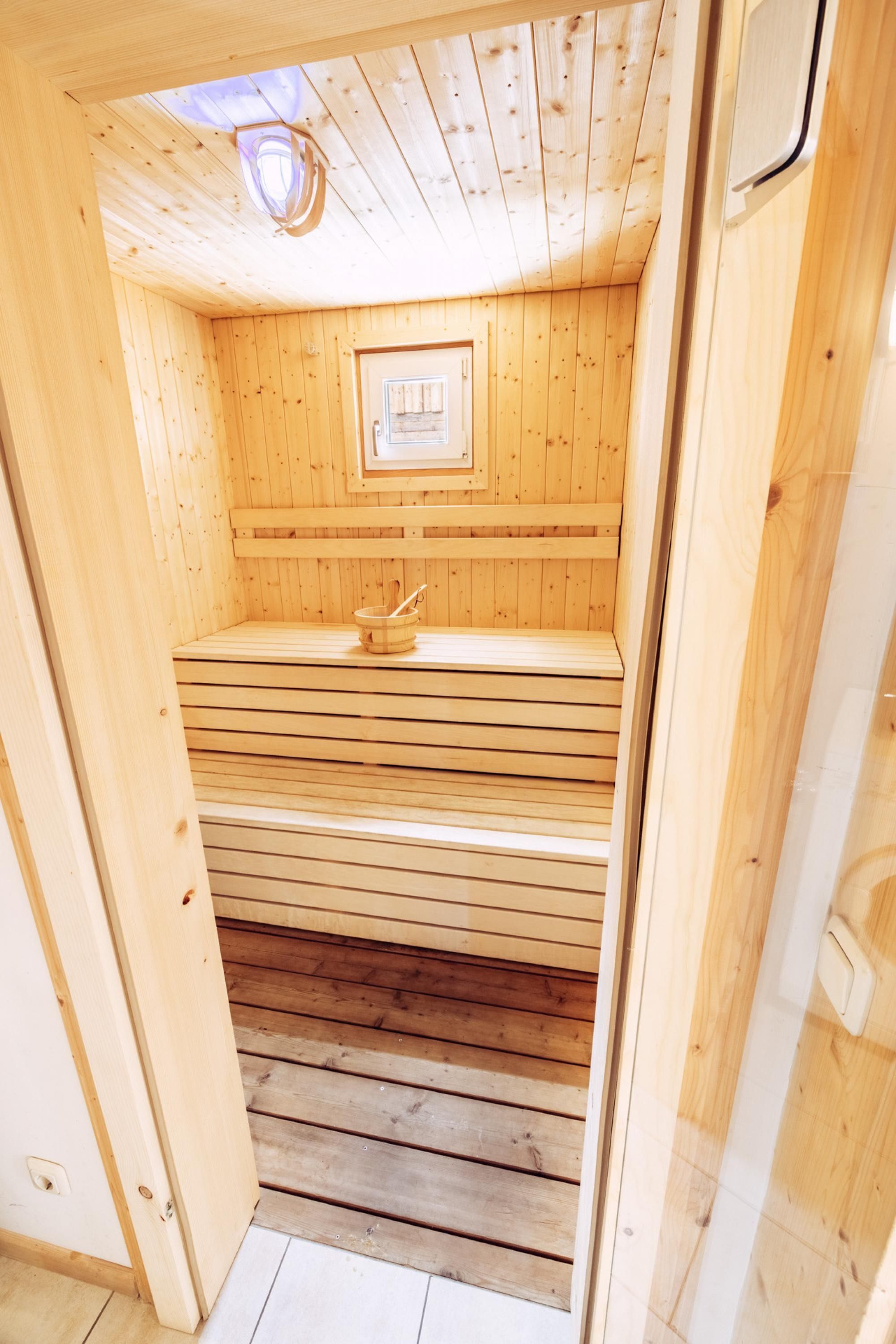 A wooden sauna with benches and a small window.