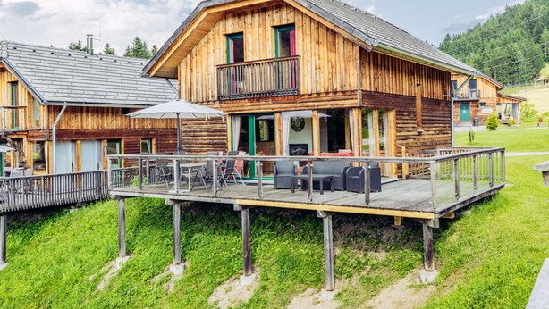 Una baita in legno con balcone e zona relax all'aperto.