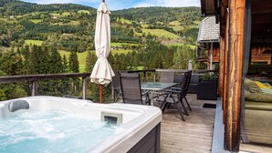 Una vasca idromassaggio su un pontile di legno con vista su una valle boscosa.