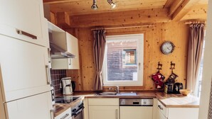 A compact kitchen with white cabinets, a stove, a sink, and a window with curtains. - 025 W5 in St Georgen am Kreischberg (Sankt Georgen am Kreischberg)