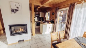 A cozy cabin interior with a fireplace, wooden dining table, and a kitchen area. - 025 W5 in St Georgen am Kreischberg (Sankt Georgen am Kreischberg)