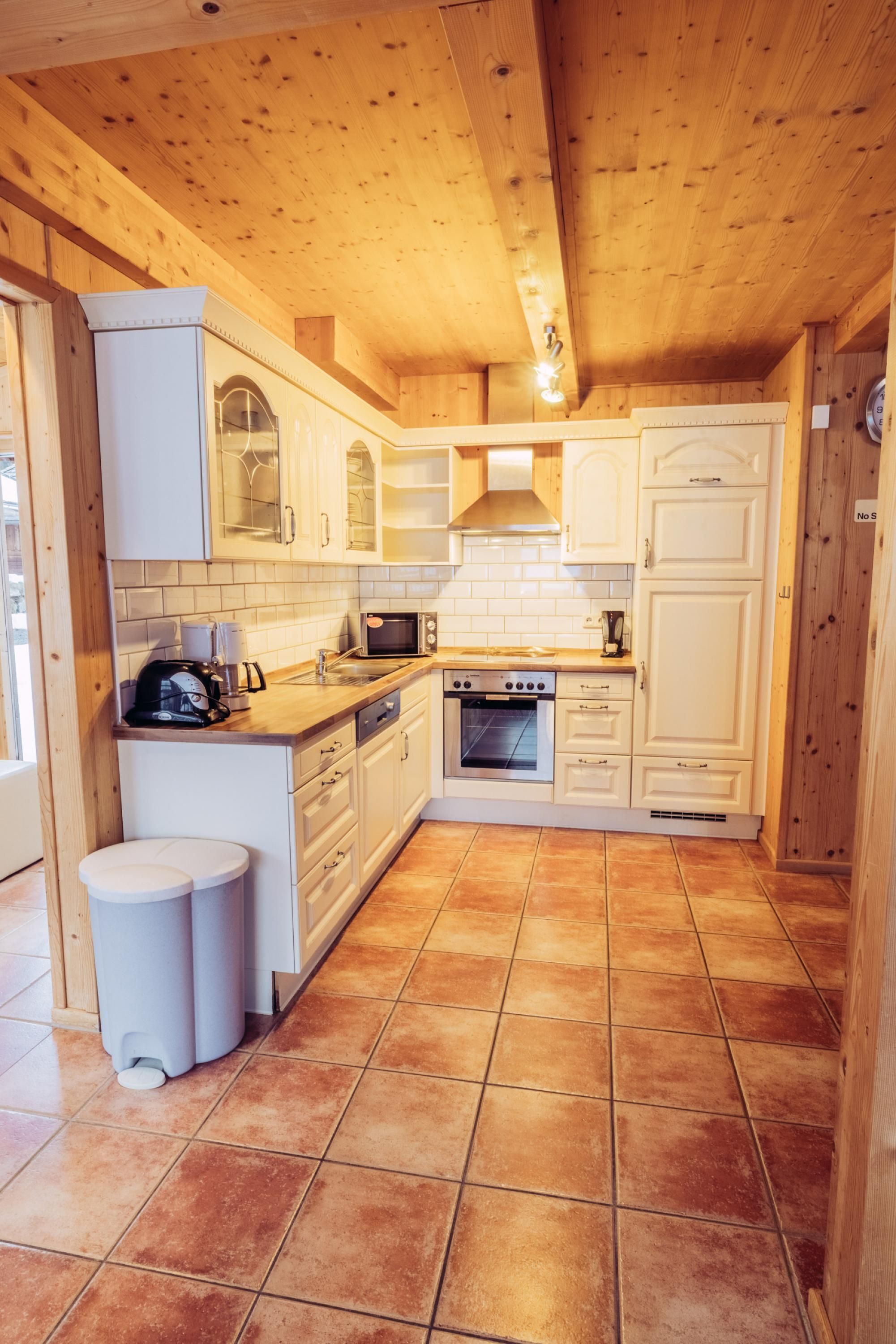 A compact kitchen with wooden cabinets, a microwave, an oven, and a sink.