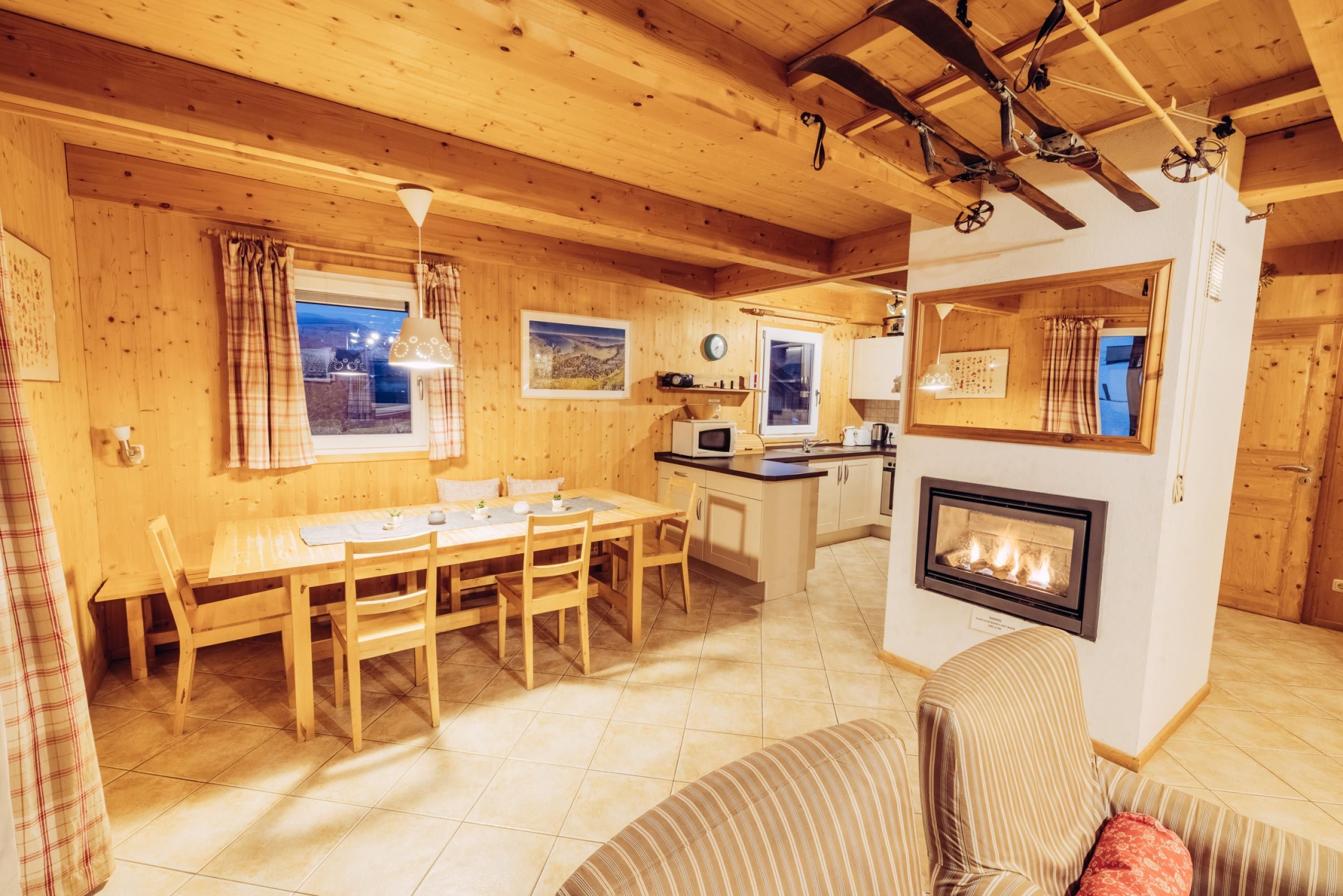 A cozy wooden interior with a dining area, kitchen, and fireplace.