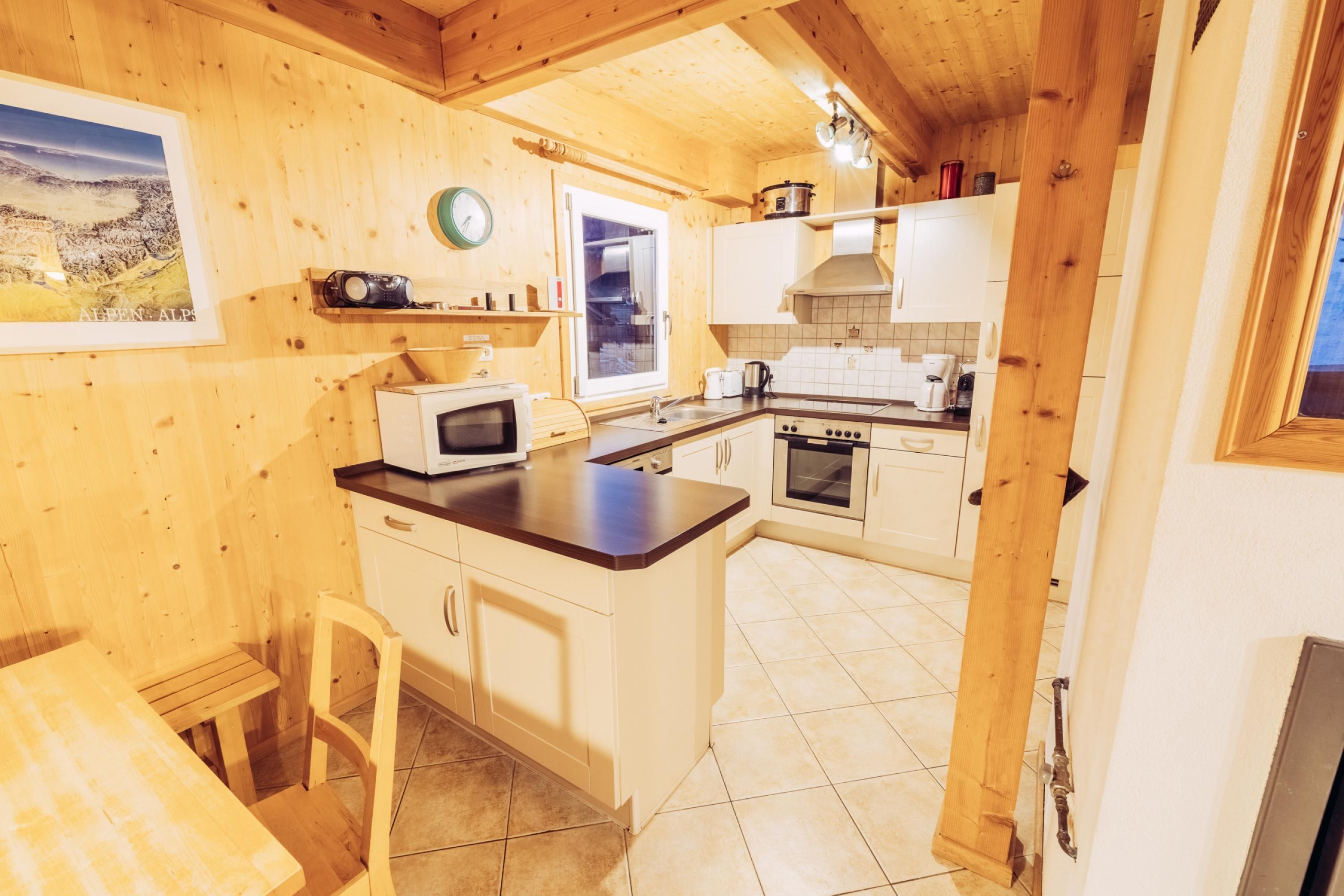 A wooden interior with a kitchen area, including a microwave, oven, and sink.