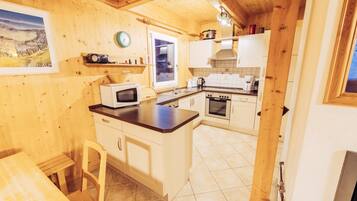 A wooden interior with a kitchen area, including a microwave, oven, and sink.