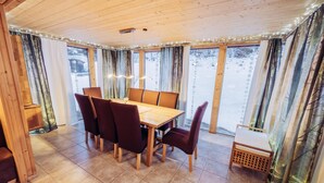 A wooden-paneled room with a dining table and chairs, large windows with curtains, and a small wooden bench. - 033 W13 in St Georgen am Kreischberg (Sankt Georgen am Kreischberg)