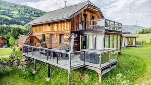 A wooden chalet with a balcony and a glass enclosure, set in a green valley with hills in the background. - 033 W13 in St Georgen am Kreischberg (Sankt Georgen am Kreischberg)