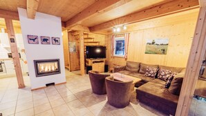A cozy cabin interior with a fireplace, wooden walls, a sofa, and a television. - 033 W13 in St Georgen am Kreischberg (Sankt Georgen am Kreischberg)
