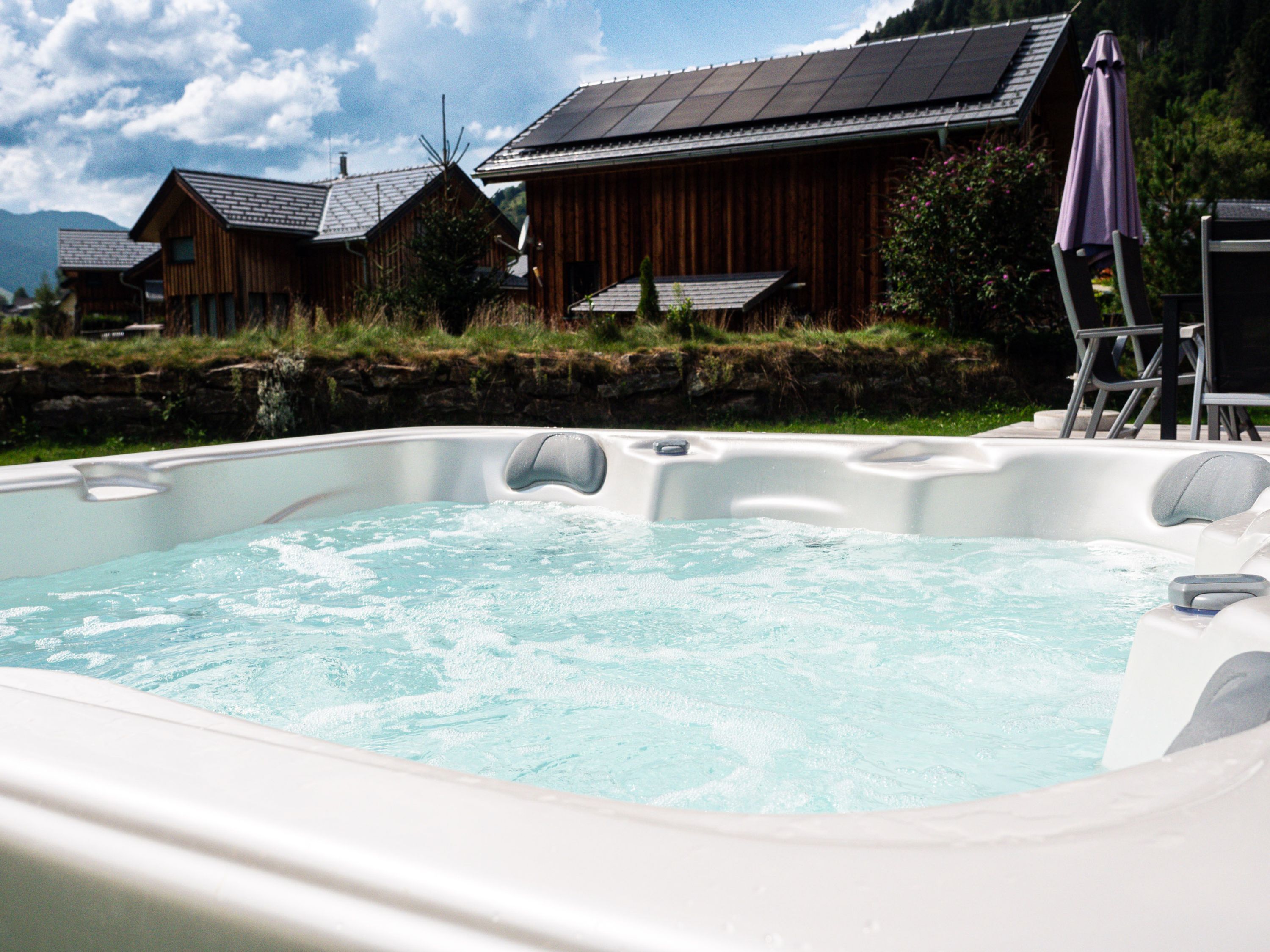 Een hottub met een houten terras en uitzicht op een berg.