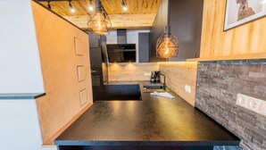Une cuisine moderne avec un plan de travail foncé, des meubles en bois et des luminaires suspendus.