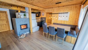 Un intérieur chaleureux en bois, avec une cheminée, un coin repas et une cuisine.
