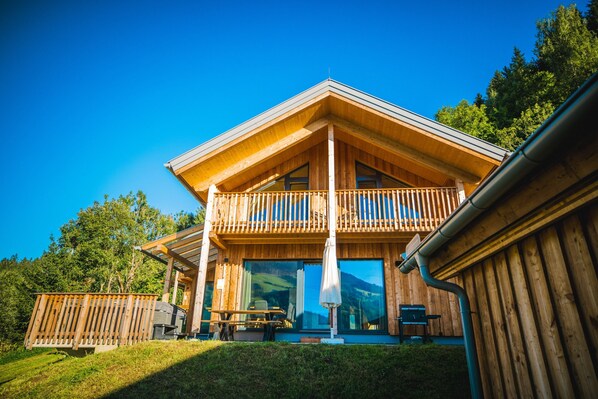 A wooden cabin with a balcony, large windows, and a dining area with outdoor seating. - 040 W19 in St Georgen am Kreischberg (Sankt Georgen am Kreischberg)