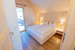 A wooden-paneled bedroom with a bed, bedside lamps, and a view of a snowy landscape through a door. - 040 W19 in St Georgen am Kreischberg (Sankt Georgen am Kreischberg)