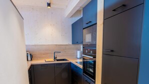 Eine moderne Küche mit Holzbalkendecke, eingebautem Backofen und einem großen Kühlschrank.