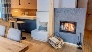 A cozy cabin interior with a fireplace, wooden furniture, and a kitchen area.